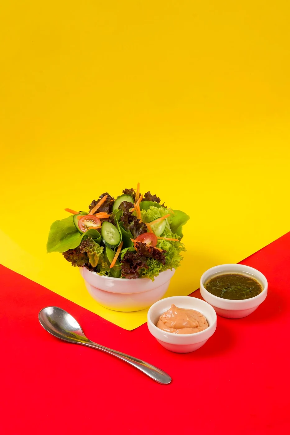 Garden salad with dressings on a bright yellow and red backdrop